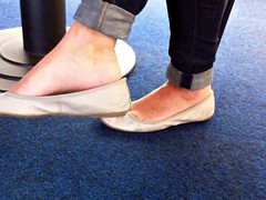 Candid dangling in grey flat barefeet